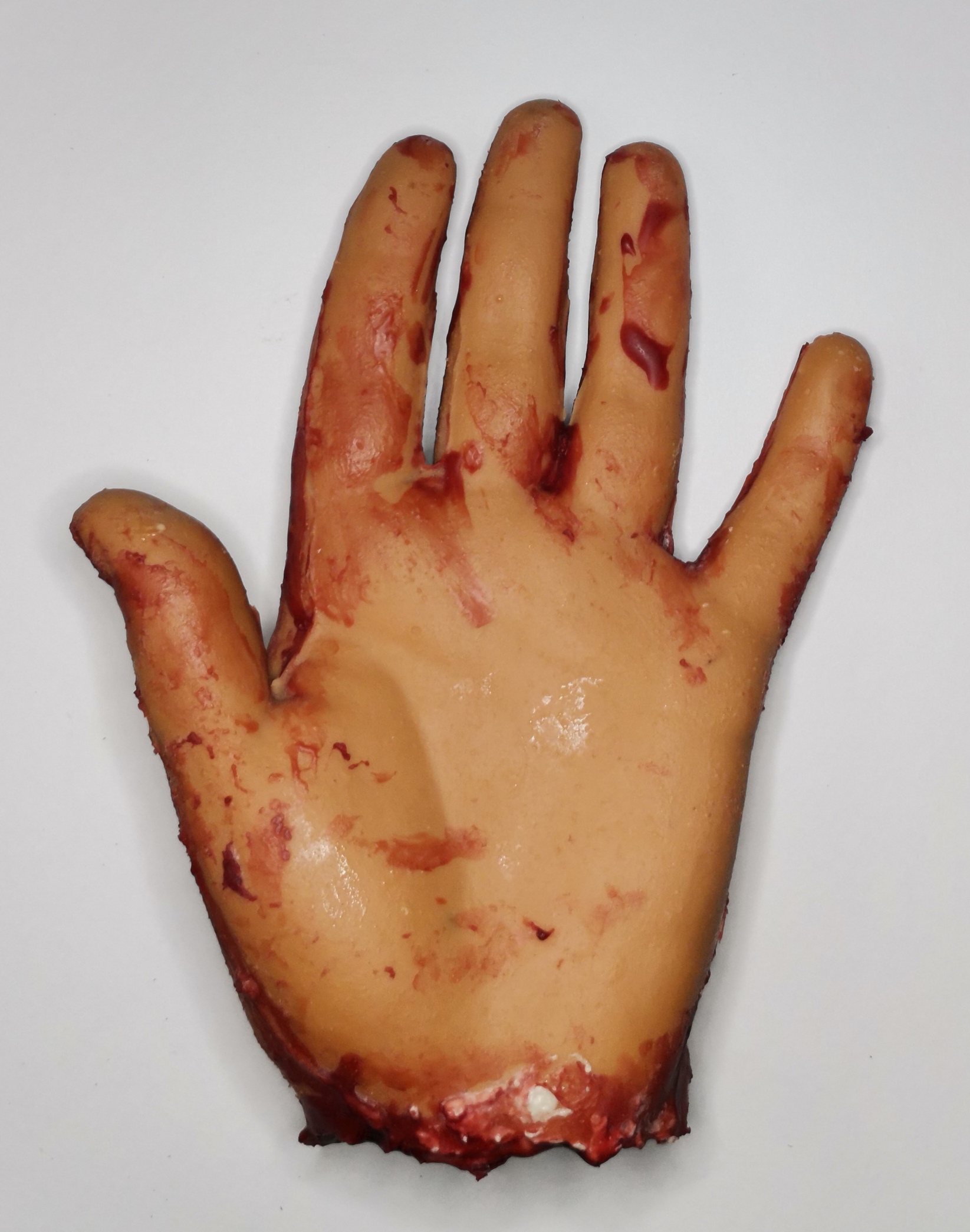 Una mano de simulación con apariencia de piel humana, manchada de color rojo, que simula heridas o sangre.